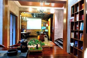 Un interior acogedor con piso de madera, un pequeño jardín interior, una estantería y un comedor con mesa y sillas.