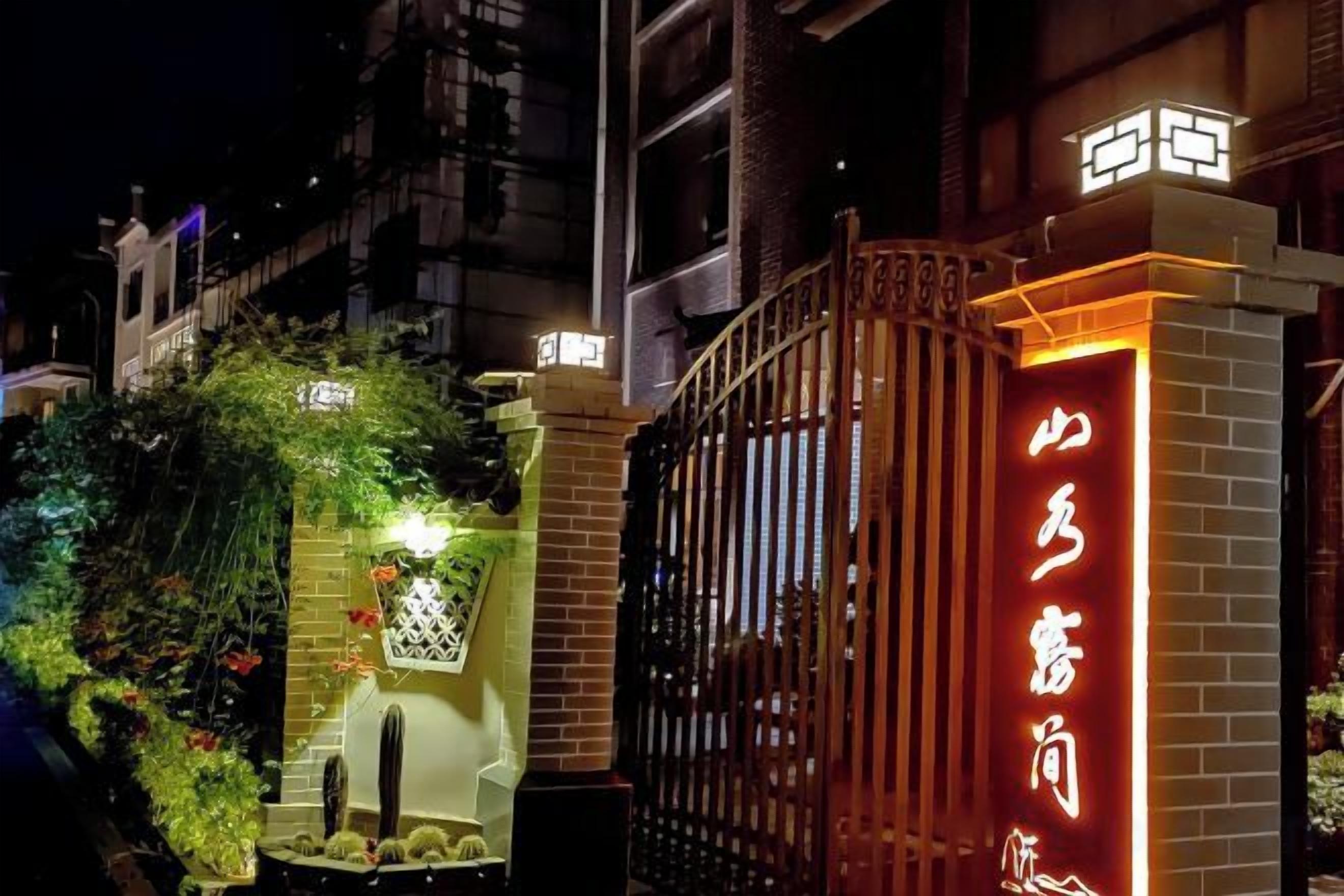 A gated entrance with illuminated signage, a brick wall, and a metal gate.