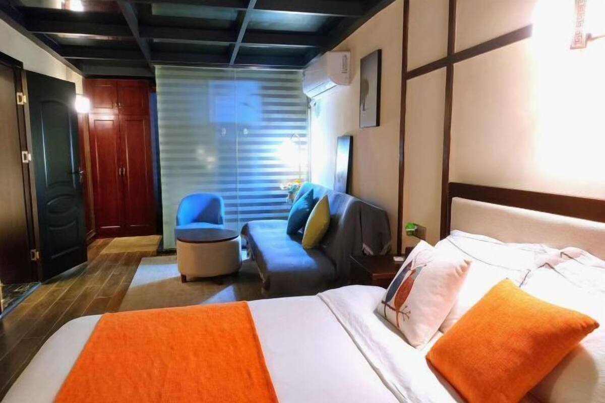 Ein Hotelzimmer mit Bett, einer Couch, einem Sessel und einem Fenster mit Jalousien.