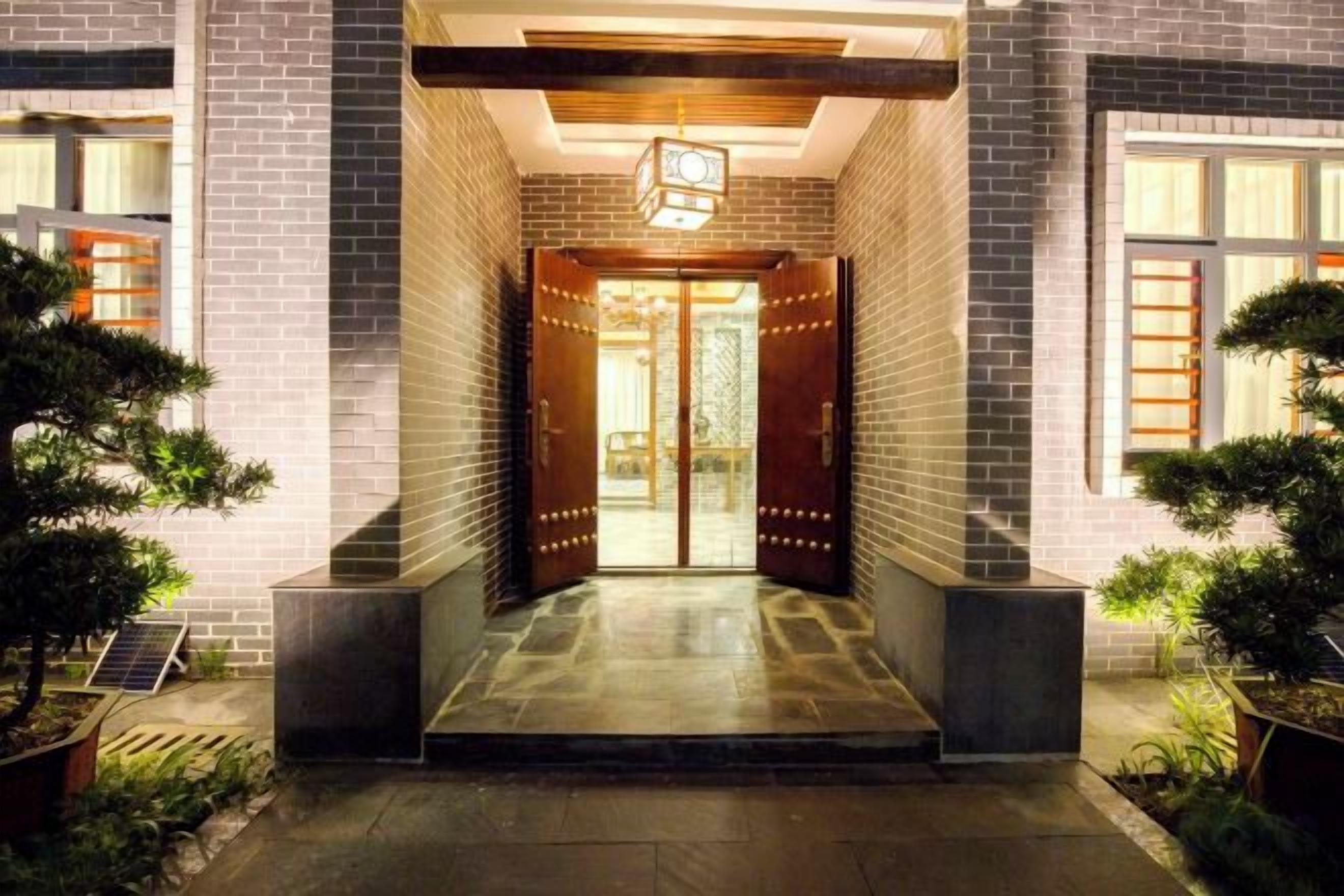 Una entrada de edificio con puertas dobles, una luminaria arriba y un camino empedrado que conduce a las puertas.