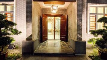 Una entrada de edificio con puertas dobles, una luminaria arriba y un camino empedrado que conduce a las puertas.