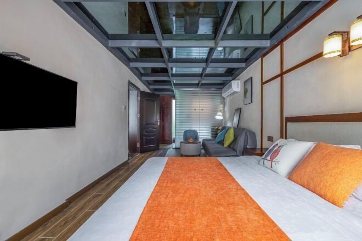 Habitación de hotel con cama, sofá, una mesita y televisor montado en la pared.