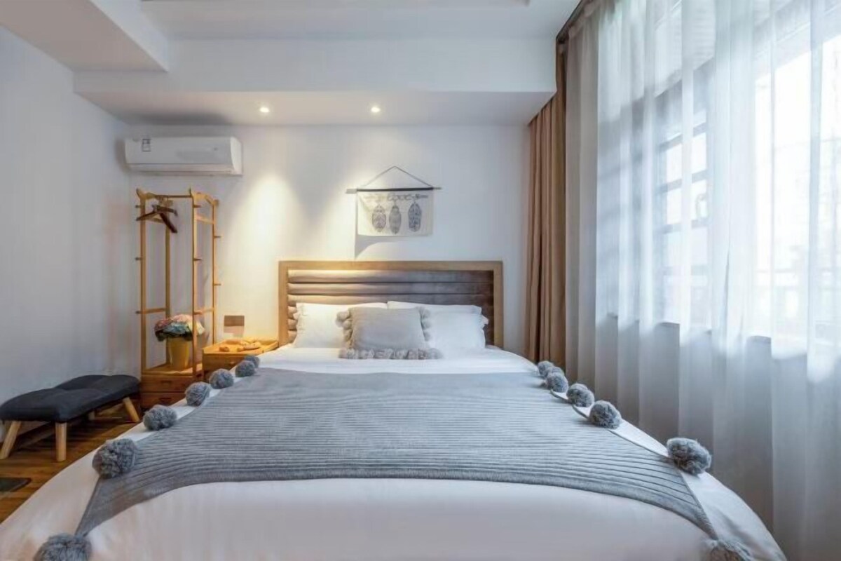 Un dormitorio ordenado con cama, mesita de noche y lámpara colgante.