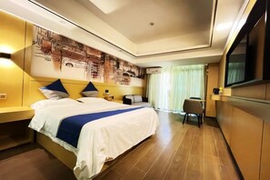 A hotel room with a large bed, a desk, a chair, a television, and a wall-mounted artwork.