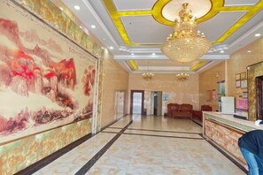 A hotel lobby with a reception desk, a large mural, and a chandelier. - Ledong Novartis Business Hotel (Ledong)