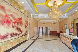 Um saguão de hotel com uma mesa de recepção, um grande mural e um candelabro.