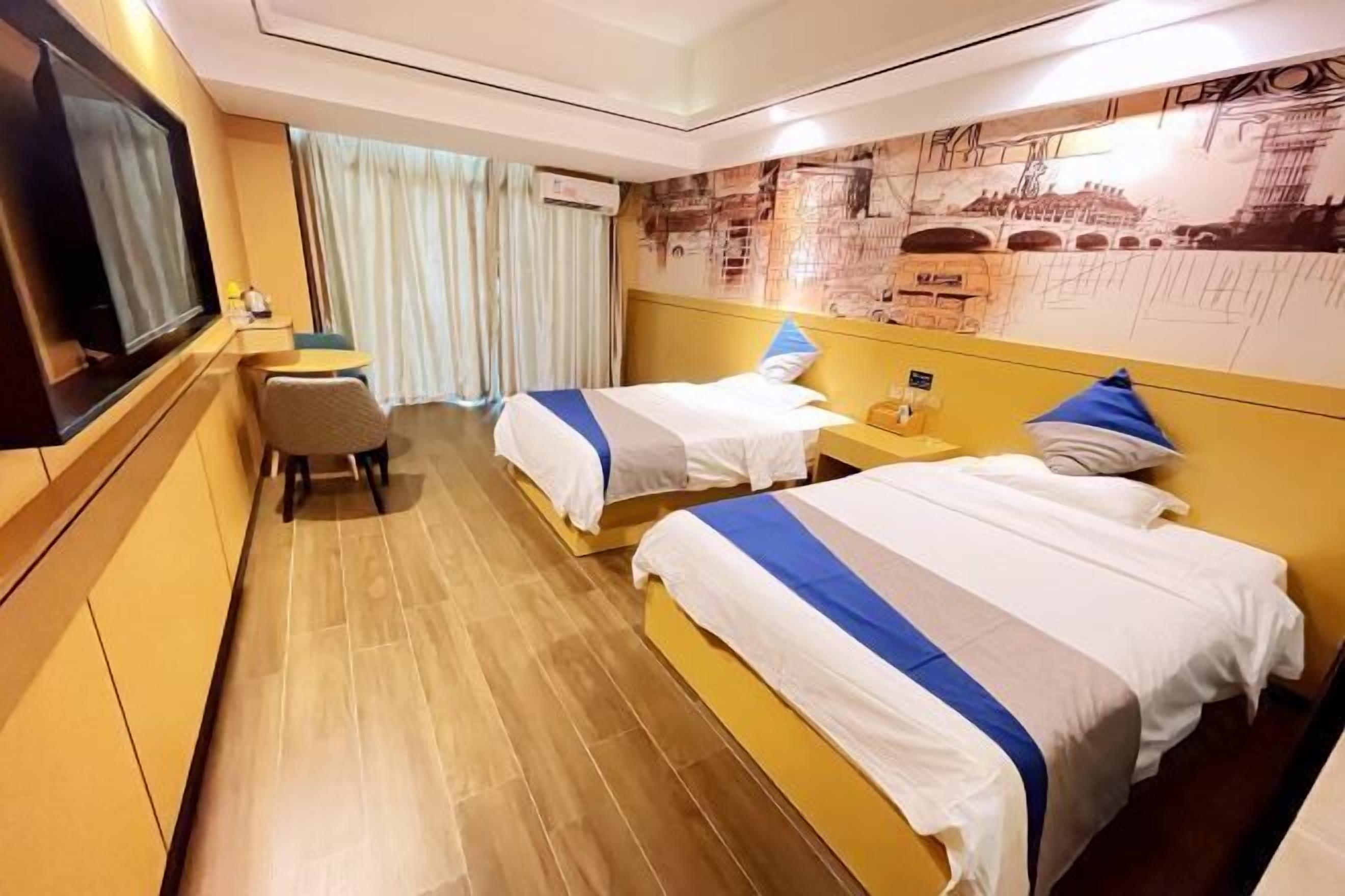 A hotel room with two beds, a TV, a desk, and a chair.