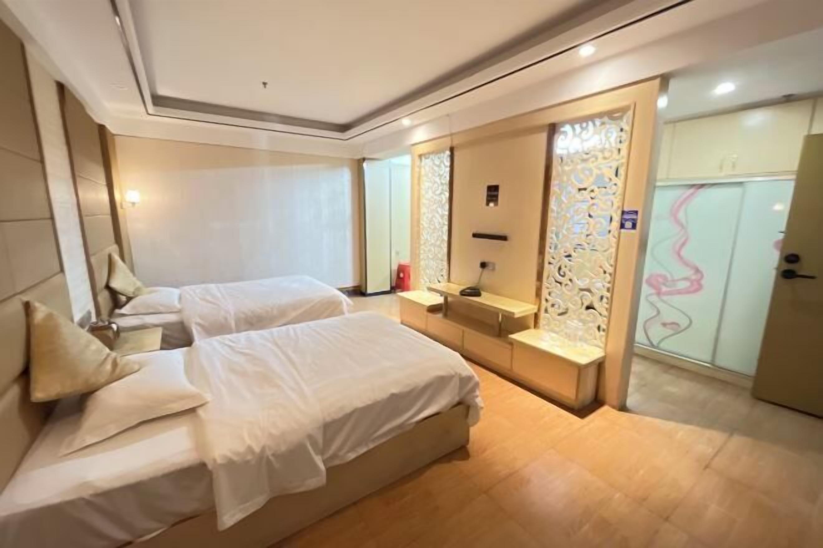 Ein Hotelzimmer mit zwei Betten, einem Schminktisch und einem dekorativen Raumteiler.