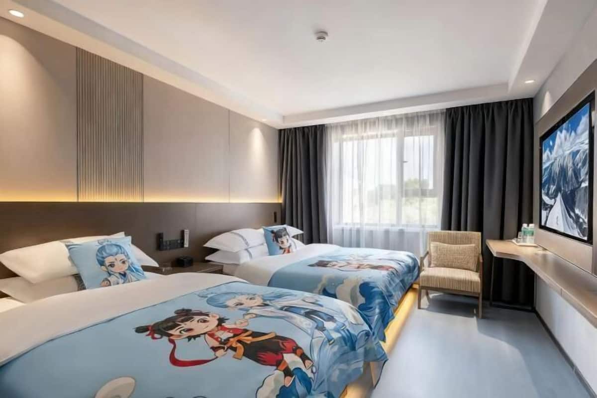 A hotel room with two beds, a desk, a chair, a TV, and a window with curtains.