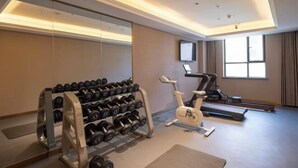 A gym with a mirrored wall, dumbbells, an elliptical, and a treadmill. - Yinhe Hotel (Burqin)