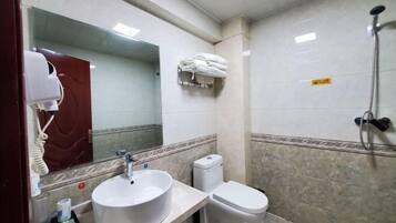 A bathroom with a white sink, toilet, and a towel rack with towels.