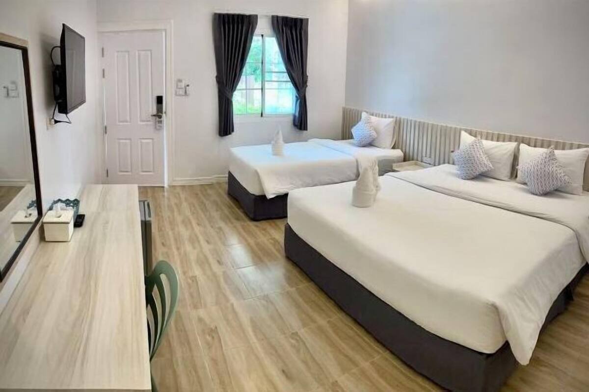 Hotellihuoneessa on suuri sänky, pienempi sänky, työpöytä ja televisio.