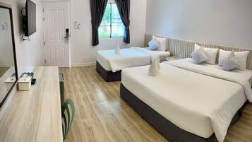 A hotel room with a large bed, a smaller bed, a desk, and a television.