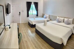 Una habitación de hotel con una cama grande, una cama más pequeña, un escritorio y un televisor.