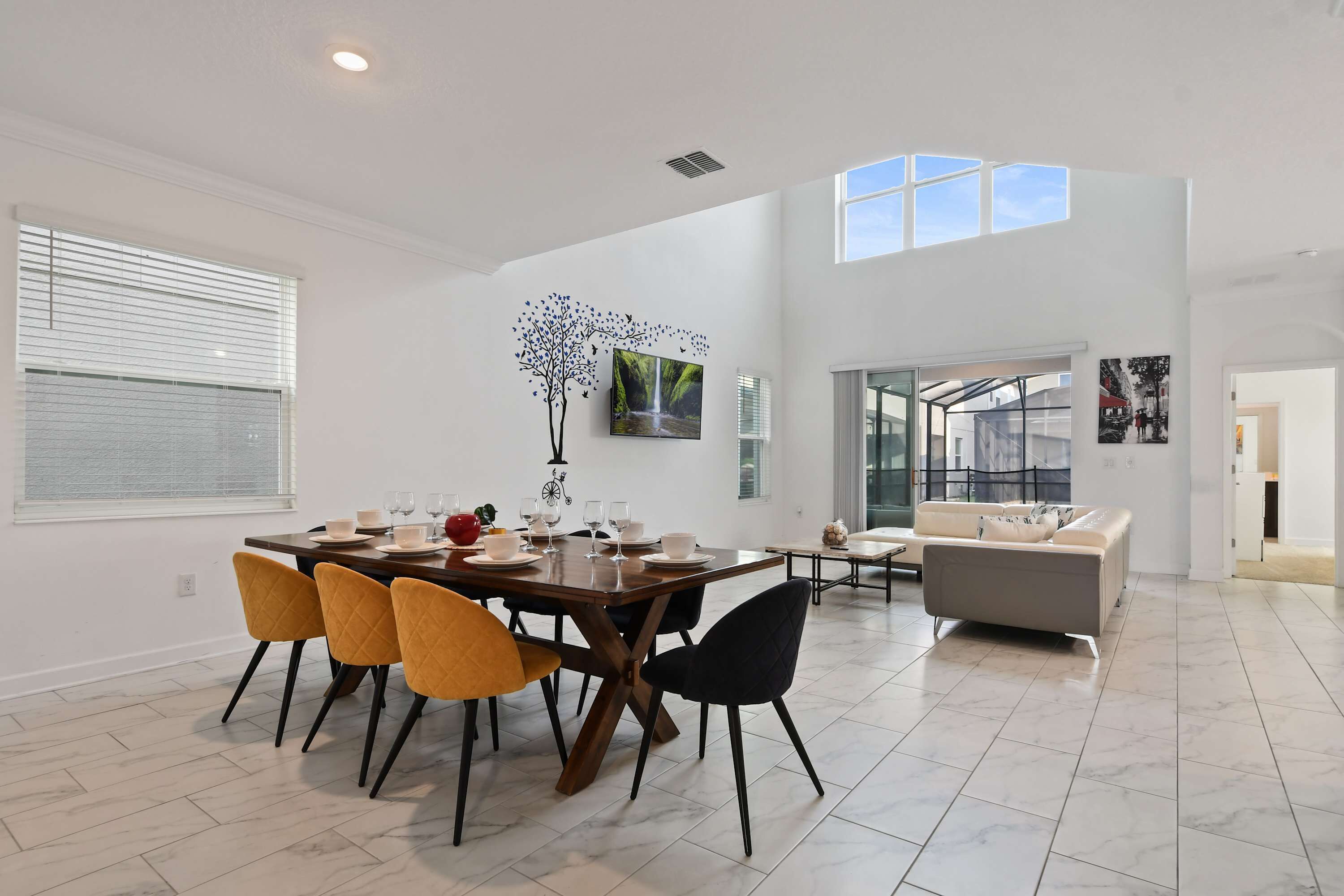 Un vaste espace de vie doté d’un haut plafond, d’une table à manger avec des chaises et d’un canapé.