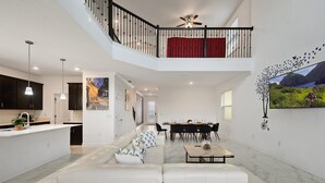 A spacious living area with a high ceiling, a dining area, and a kitchen. - Large 5BR Home w Pool, Princess Room, Resort Access (Kissimmee)