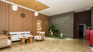 A modern lobby with a wooden wall, a reception desk, a sofa, a coffee table, and a decorative plant. - Shankee Hotel (Nanchang Chengbihu Park) (Nanchang County)