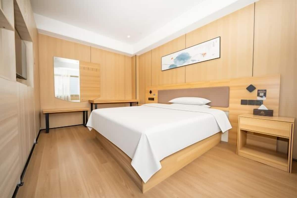 Een moderne hotelkamer met een groot bed, houten lambrisering, een nachtkastje en een wanddecoratie.