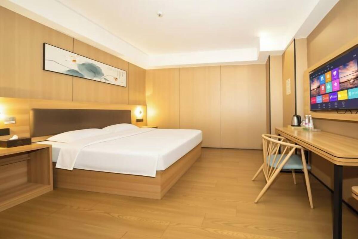 Een hotelkamer met een bed, nachtkastje, bureau, stoel en een televisie.