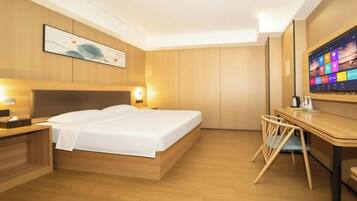 A hotel room with a bed, bedside table, desk, chair, and a television.
