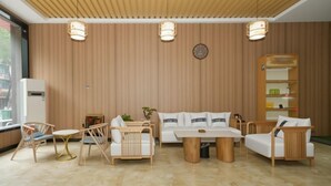 A modern living room with a wooden wall, a sofa, two armchairs, a coffee table, and a bookshelf. - Shankee Hotel (Nanchang Chengbihu Park) (Nanchang County)