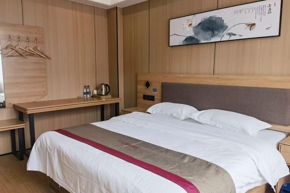 A hotel room with a bed, a desk, and a wall-mounted artwork.