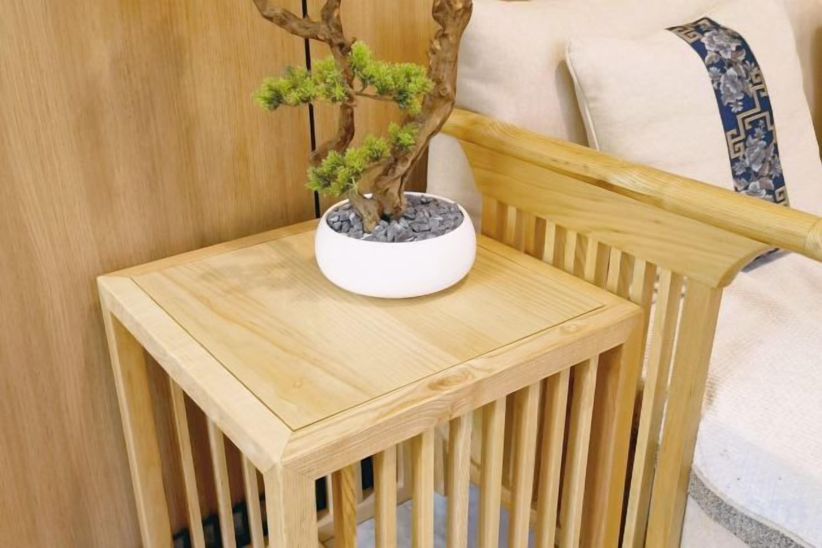 Una silla de madera con un bonsái sobre una pequeña mesa.