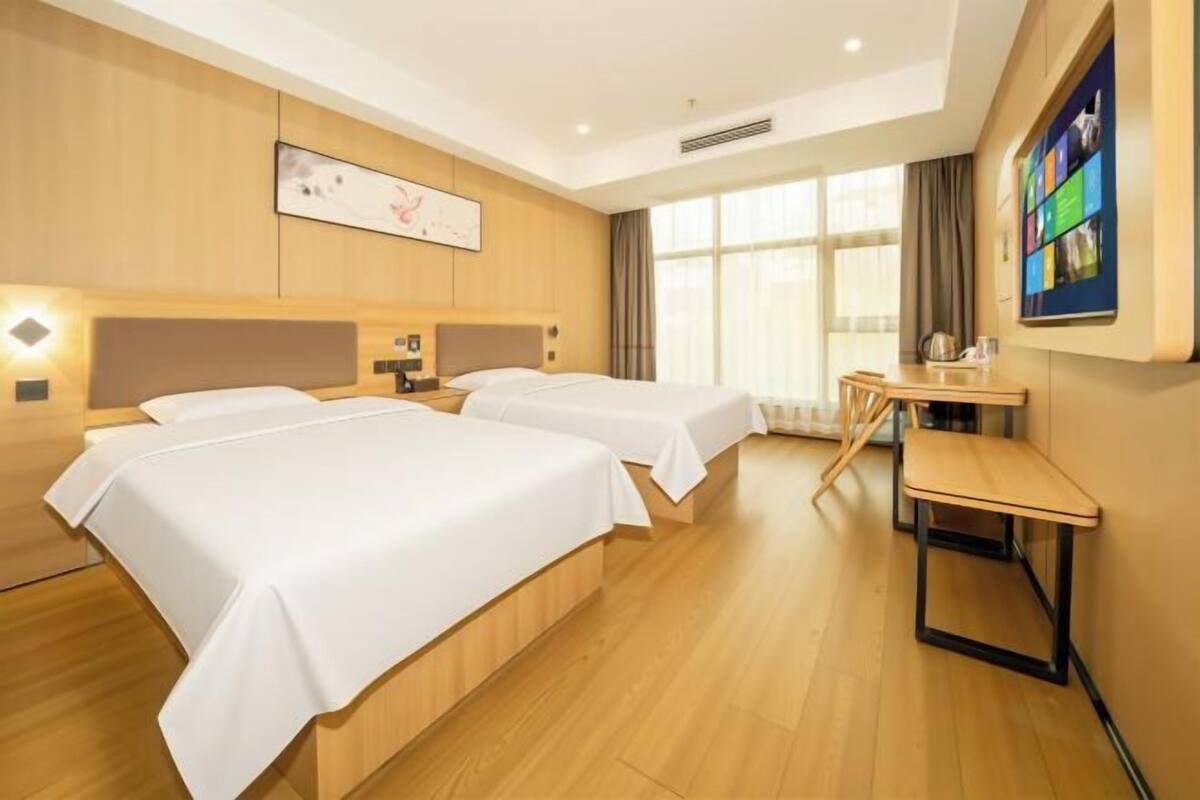 Een hotelkamer met twee bedden, een bureau en een groot raam.