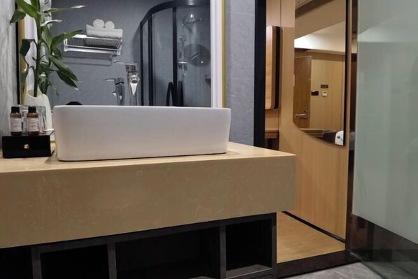 A modern bathroom with a white sink, a glass shower enclosure, and a wooden door. - Shankee Hotel (Nanchang Chengbihu Park) (Nanchang County)