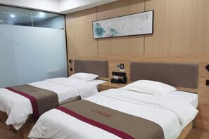 A hotel room with two beds, a wooden headboard, a wall-mounted artwork, and a bedside table with a phone and a small item. - Shankee Hotel (Nanchang Chengbihu Park) (Nanchang County)