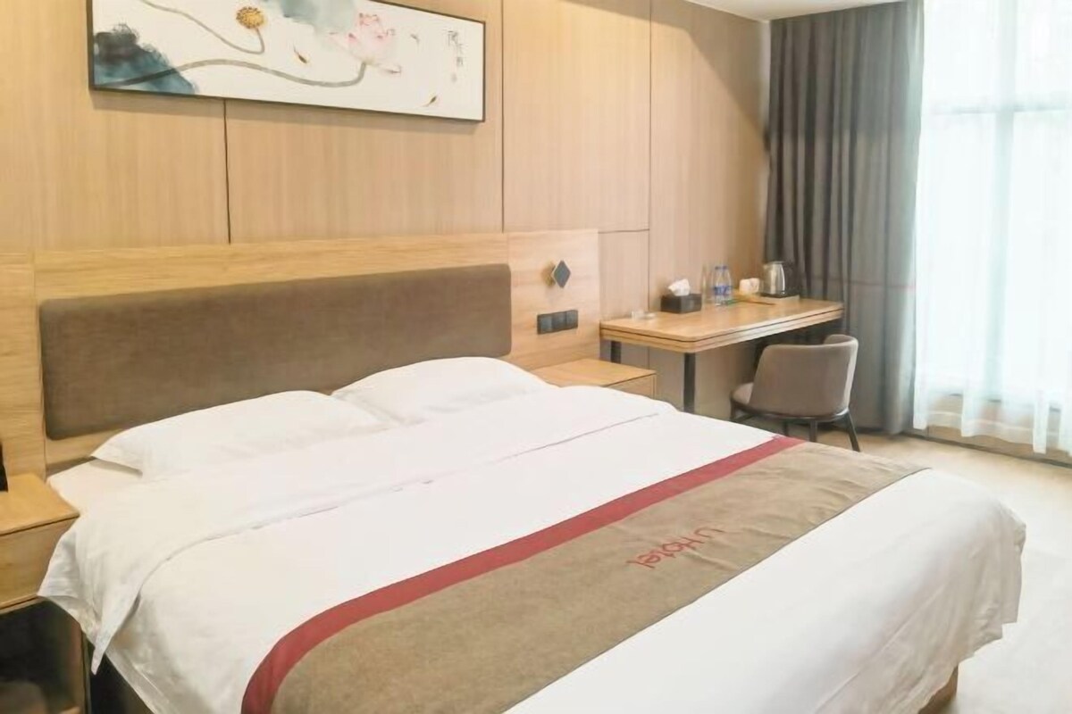 A hotel room with a large bed, a desk, and a chair.