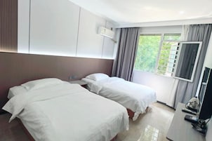 Habitación de hotel con dos camas, televisión y ventana con cortinas.