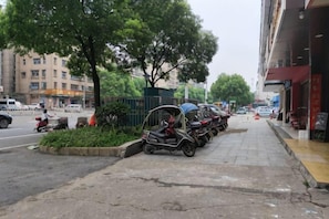 Rua com veículos estacionados, calçada e edifícios.