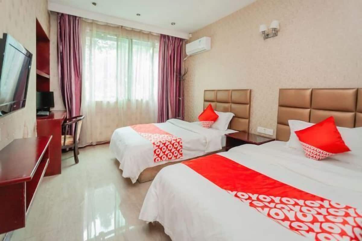 A hotel room with two beds, a TV, and a desk.