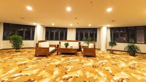 A spacious room with a patterned carpet, a sofa set, and large windows. - longdeguojifandian (Longde)