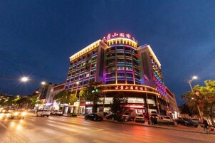 Un hotel de varios pisos con letreros iluminados y una fachada curva.