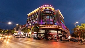 A multi-story hotel with illuminated signage and a curved facade. - longdeguojifandian (Longde)