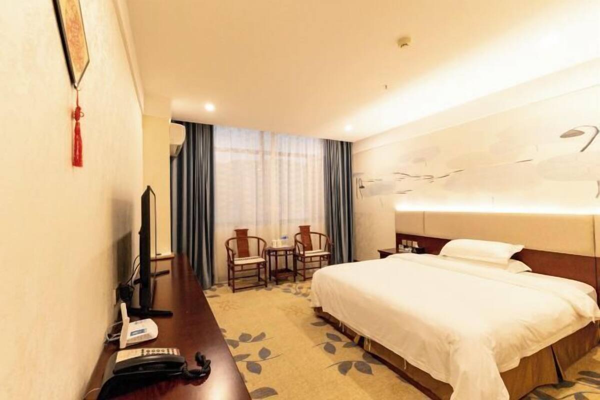 Une chambre d’hôtel comprenant un lit, un bureau avec un téléphone, une chaise et un téléviseur.