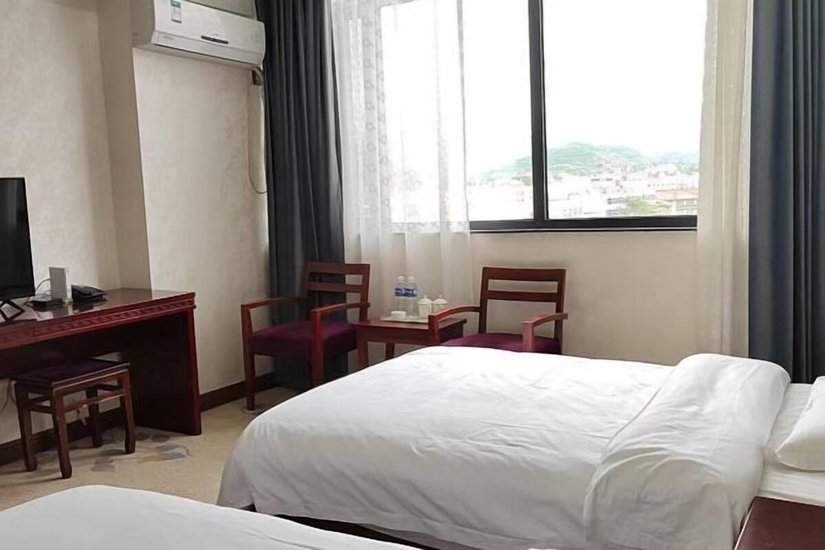 Une chambre d’hôtel équipée d’un lit, d’un bureau, d’une chaise, d’une télévision et d’une fenêtre donnant sur un paysage agréable.