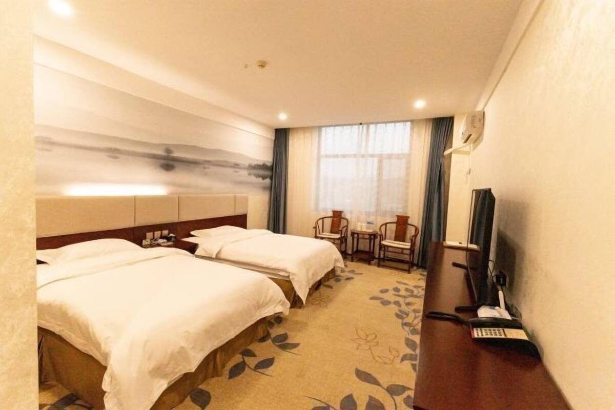 Une chambre d’hôtel avec deux lits, un bureau avec un téléphone et une télévision.