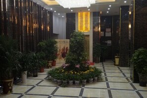 Un vestíbulo con suelo de baldosas, plantas en macetas y una columna central.