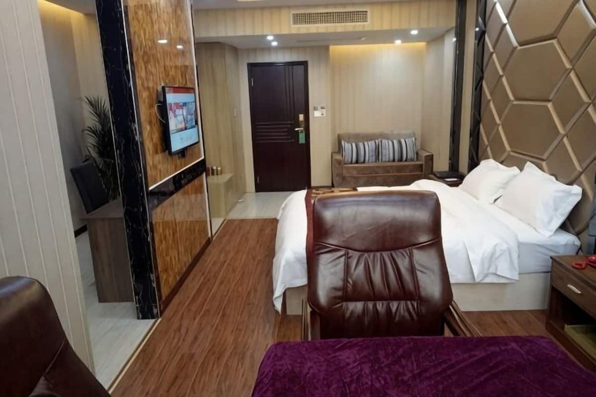 Una habitación de hotel con una cama, zona de estar, televisor y una pared de madera.