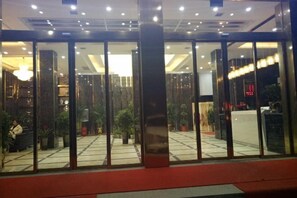 A hotel entrance with a glass door, a reception desk, and a chandelier. - Tongcheng Huaxu International Hotel (Tongcheng)