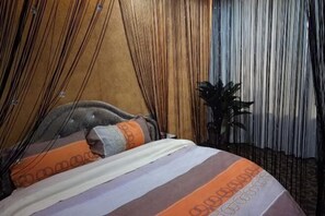Ein Bett mit gestreifter Bettwäsche, einem Kopfteil und einer Pflanze daneben.