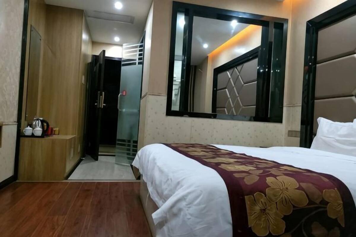 Habitación de hotel con cama, espejo, armario y puerta que da a un baño.