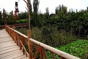 A wooden bridge with railings, surrounded by greenery. - Anargvl Manor (Turpan)