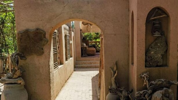 A corridor with arches, stone sculptures, and a tiled floor. - Anargvl Manor (Turpan)
