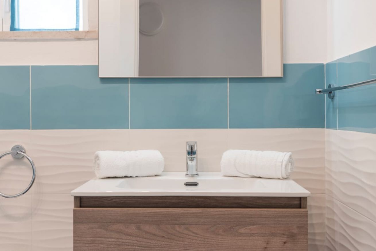 A bathroom with a sink, two towels, a mirror, and a towel rack.