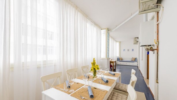 Un coin repas avec une table dressée pour quatre personnes, un canapé en arrière-plan et un chauffe-eau fixé au mur.
