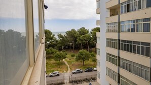 Un immeuble de grande hauteur doté de grandes fenêtres donnant sur un parking et sur un espace verdoyant avec des arbres.